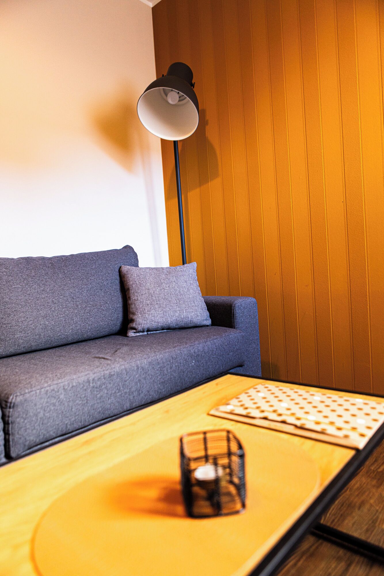 Una sala de estar moderna con un sofá gris, una mesa de centro de madera y una lámpara de pie.