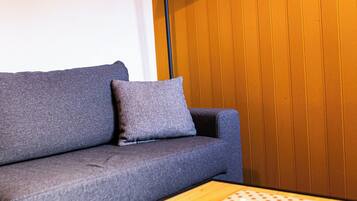 Una sala de estar moderna con un sofá gris, una mesa de centro de madera y una lámpara de pie.