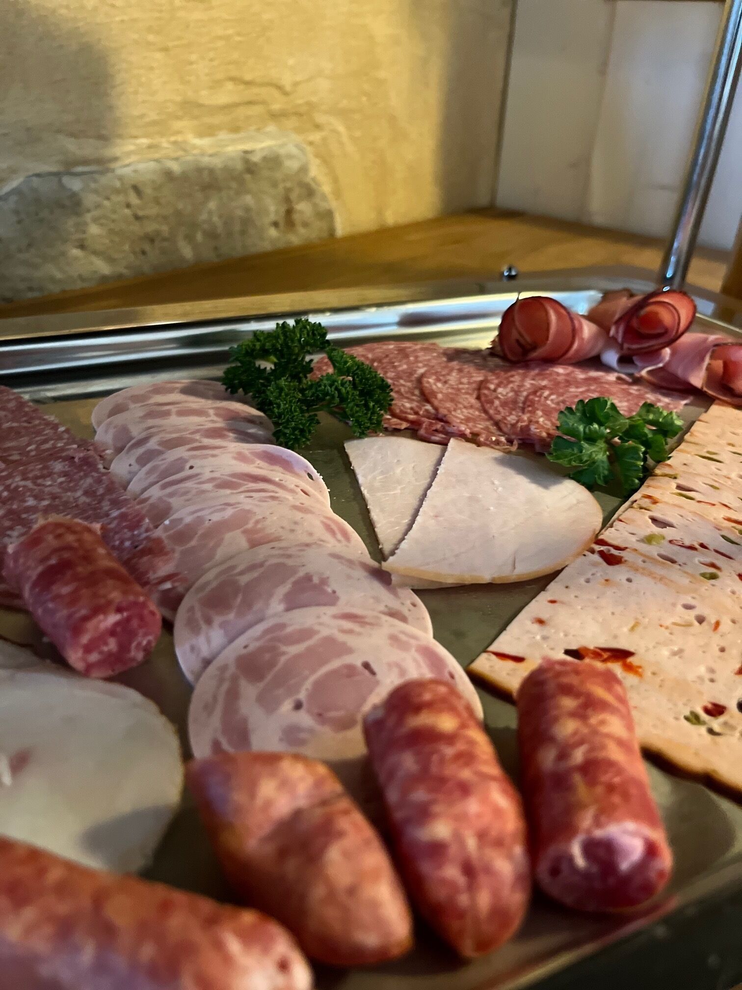 A variety of meats including sausages, salami, and sliced ham arranged on a tray.