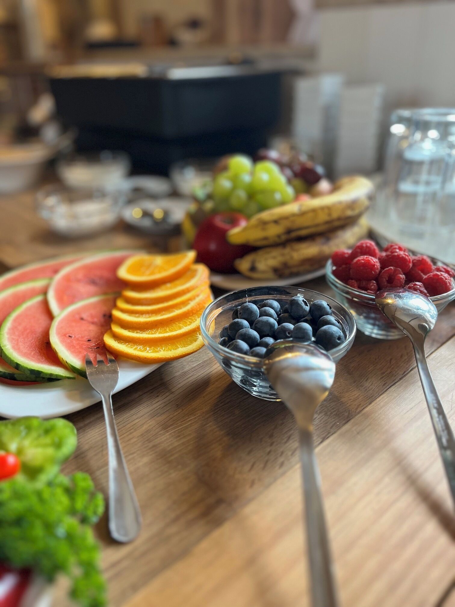 Ein Holztisch mit Wassermelone, Orangen, Blaubeeren, Himbeeren und Trauben.