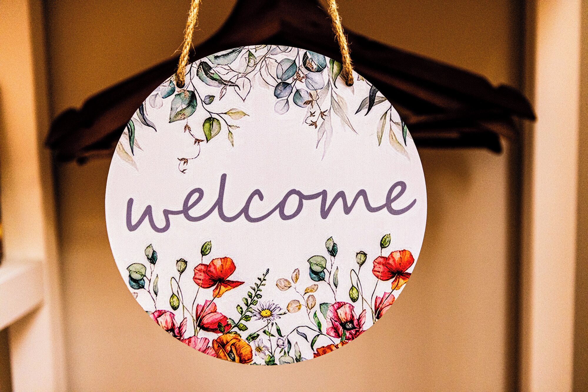 Un letrero circular de bienvenida con motivos florales y la palabra 'welcome' en el centro.