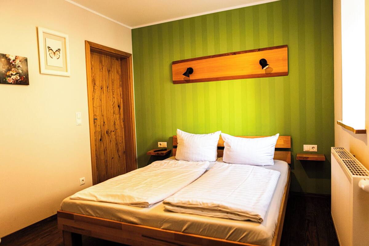 A neatly made bed with white linens, a wooden headboard, and a green-striped wall.
