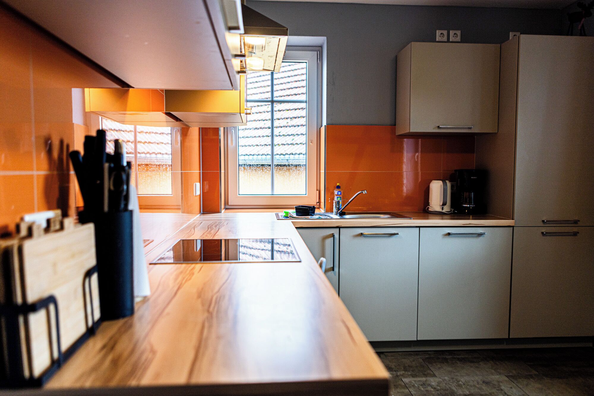 A modern kitchen with a wooden countertop, white cabinets, and a window providing natural light.