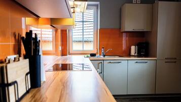 A modern kitchen with a wooden countertop, white cabinets, and a window providing natural light.