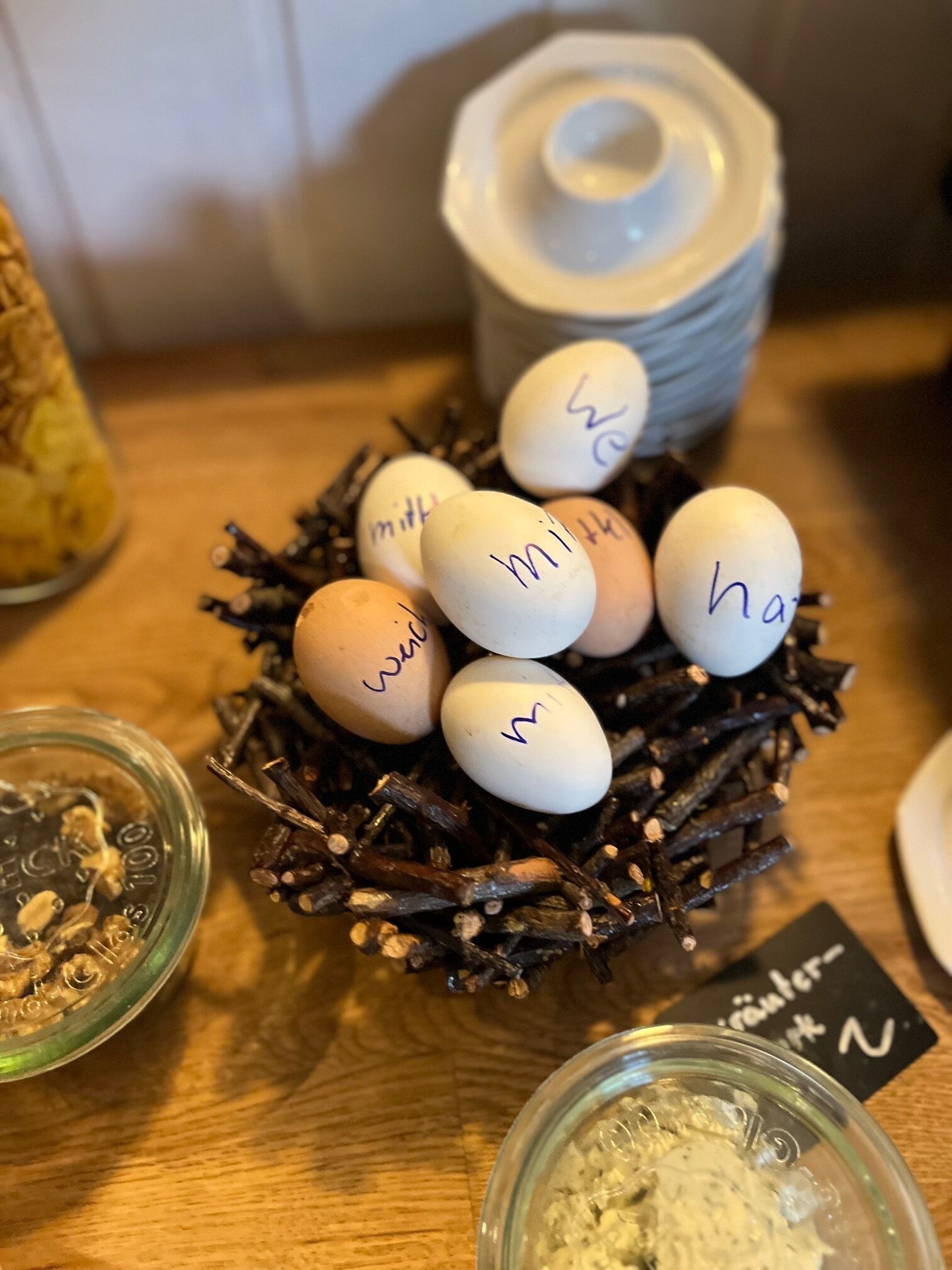 A nest of eggs with handwritten labels, a jar of what appears to be a food item, and a small sign with text.
