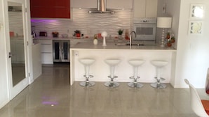 A modern kitchen with a central island, stainless steel appliances, and a red accent wall. - Charming 2-bedroom villa with terrace best view of mountain in Palm Springs area (Cathedral City)