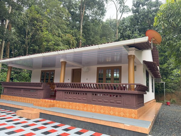 A traditional building with a covered porch, columns, and a satellite dish.