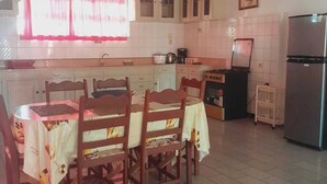 A kitchen with a dining table, chairs, cabinets, a refrigerator, and a stove. - Villa Nickerie (Nieuw Nickerie)