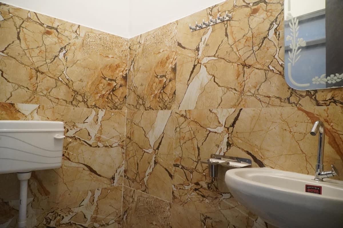 Un baño con paredes de mármol, un lavabo blanco y un inodoro.