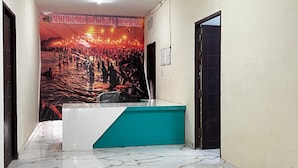 Une salle d’attente avec un bureau aux couleurs turquoise et blanche, une affiche représentant un événement très fréquenté, et une porte située sur la droite.