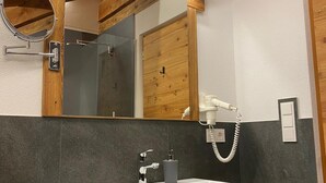 Un baño con tocador de madera, un espejo grande, un lavabo blanco y un perchero para toallas.