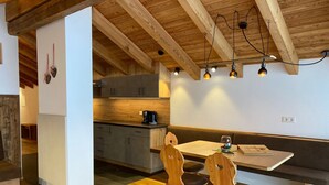Una cocina acogedora con armarios de madera, una mesa de comedor con sillas e iluminación colgante.