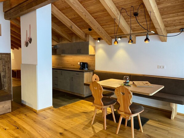 Una cocina acogedora con armarios de madera, una mesa de comedor con sillas e iluminación colgante.