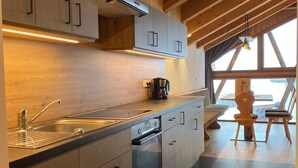 Una cocina moderna con armarios de madera, horno integrado y cafetera.
