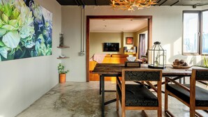 Ein modernes Wohnzimmer mit einem großen Blumenbild, einem Holzespeisetisch mit Stühlen, einer Kronleuchter und Blick auf die Stadt durch ein großes Fenster.