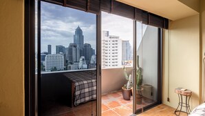 Ein Schlafzimmer mit Blick auf die Stadt, einem Bett, einem kleinen Tisch und einer Zimmerpflanze.