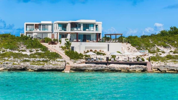 A modern two-story beachfront property with a pool, outdoor seating, and a view of the ocean. - Waterfront Villa w/ Ocean View, Plunge Pool (Long Bay)