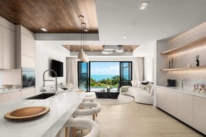 A modern kitchen with a large island, a dining area, and a view of the ocean. - Waterfront Villa w/ Ocean View, Plunge Pool (Long Bay)
