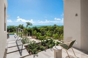 Un balcon avec vue sur l’océan et la verdure.
