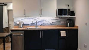 A modern kitchen with a dishwasher, a sink, a microwave, and a coffee maker.