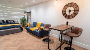 A modern living room with a sofa, a coffee table, and a wall-mounted clock.