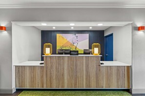 Un comptoir d’accueil au design moderne, une porte bleue et une grande œuvre d’art abstraite accrochée au mur.