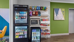 A vending machine area with snacks and drinks, a microwave, and a refrigerator. - Spark by Hilton Killeen (Killeen)