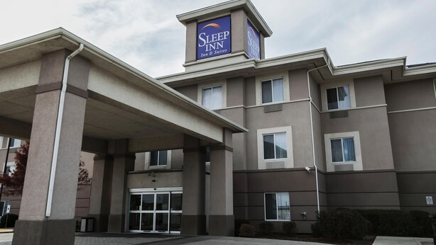 Un hotel Sleep Inn amb un cartell ben visible, entrada coberta i cel clar.
