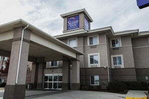 Un hôtel Sleep Inn avec une enseigne bien visible, une entrée abritée et un ciel dégagé.