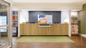 A reception area with a wooden reception desk, a large wall-mounted artwork, and shelves with various items. - Spark by Hilton Killeen (Killeen)