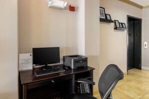 A hotel office area with a desk, computer, printer, chair, and a wall-mounted security camera. - Spark by Hilton Killeen (Killeen)