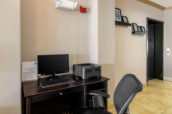 A hotel office area with a desk, computer, printer, chair, and a wall-mounted security camera. - Spark by Hilton Killeen (Killeen)
