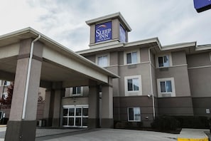 A Sleep Inn hotel with a prominent sign, a covered entrance, and a clear sky.