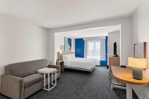 A hotel room with a bed, a sofa, a small table, a desk, a lamp, and a TV. - Spark by Hilton Killeen (Killeen)