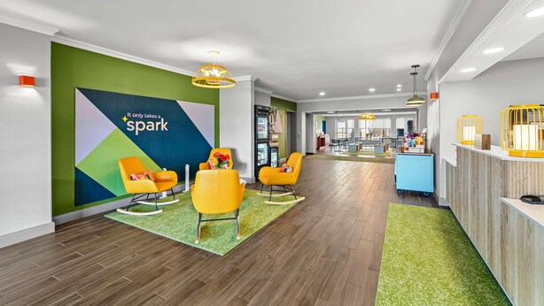 A hotel lobby with a reception desk, bright yellow chairs, a green wall with a 'Spark' sign, and a wooden floor. - Spark by Hilton Killeen (Killeen)