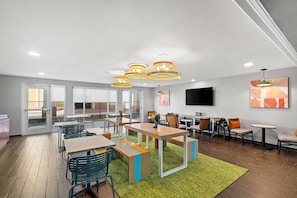 A modern dining area with tables and chairs, a green carpet, and pendant lighting. - Spark by Hilton Killeen (Killeen)