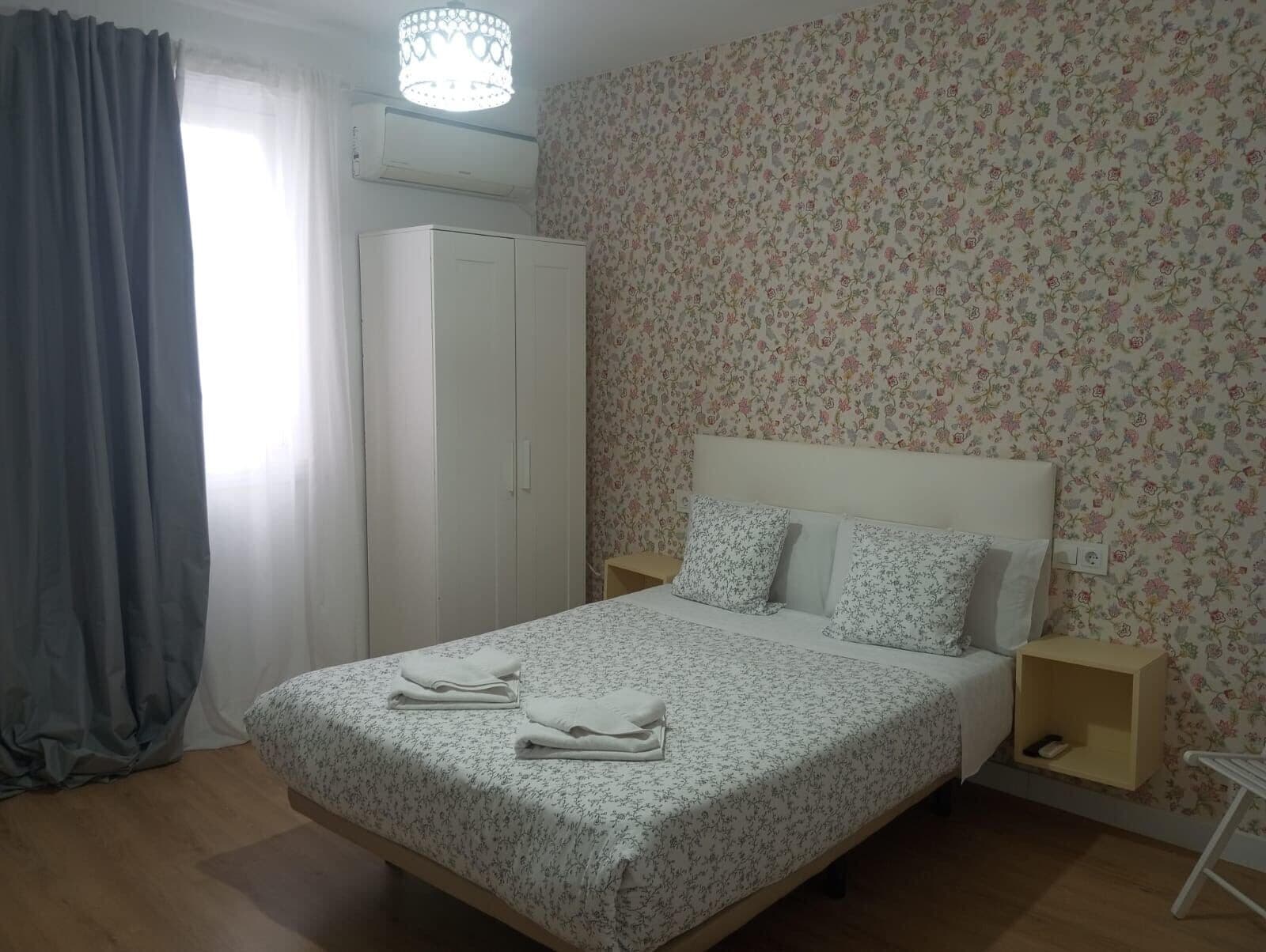 Un dormitorio con cama, armario, mesita de noche y estante en la pared.