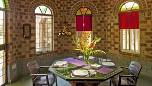 Un espace repas avec un mur en briques, des fenêtres en arc de cercle, une table ronde et des chaises.