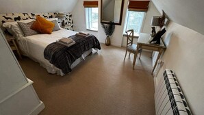 Une chambre Ă coucher comprenant un lit, une chaise, un bureau, un miroir et un radiateur.