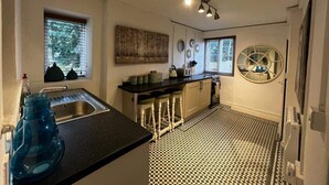 Une cuisine de taille réduite avec un sol à carreaux noirs et blancs, un évier, une cuisinière et un tabouret de bar.
