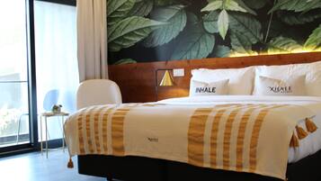 A hotel room with a large bed, a wooden headboard, and a wall mural of leaves.