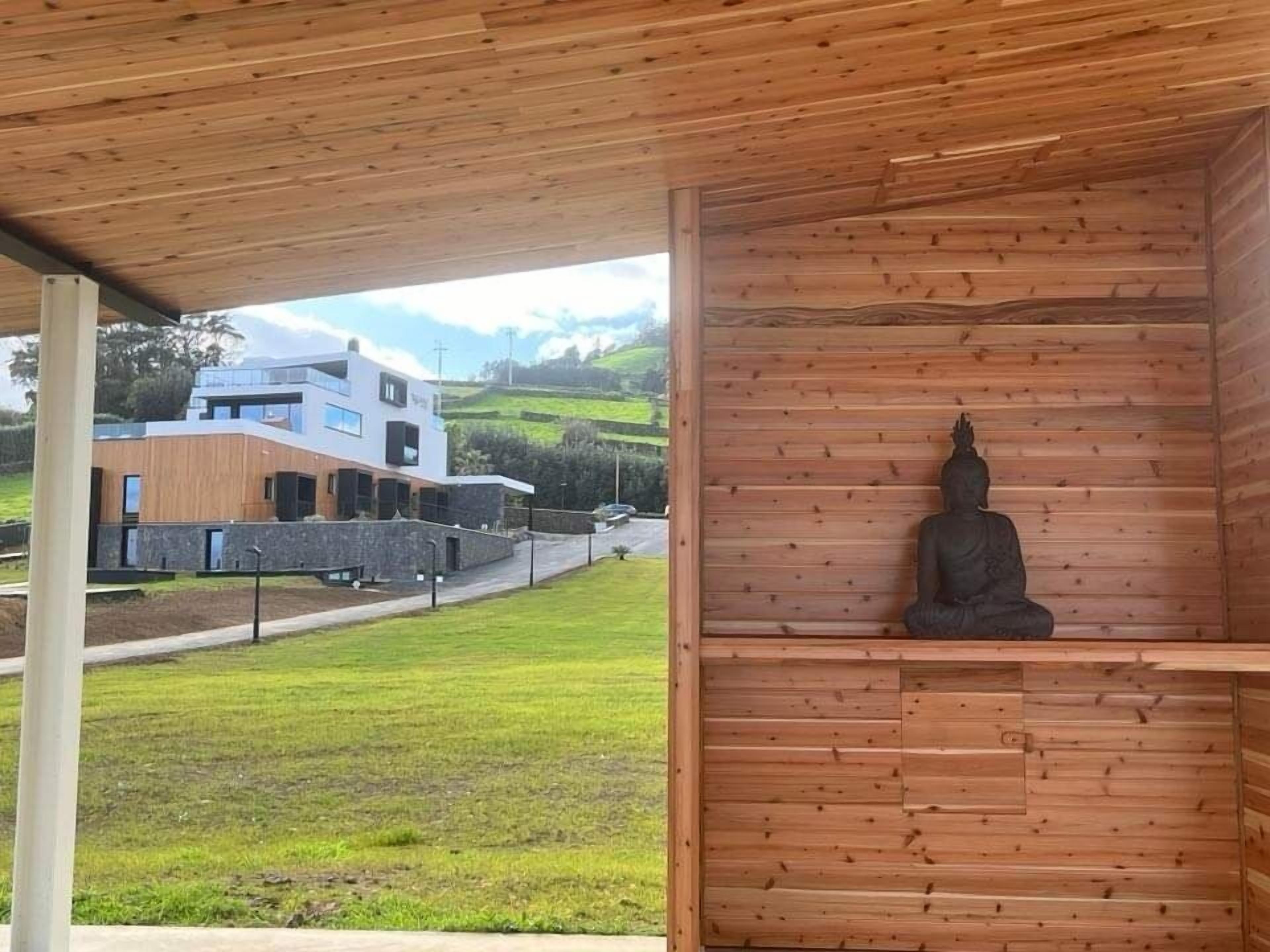 En trækonstruktion med en statue af en siddende figur, sandsynligvis Buddha, i en meditativ stilling.