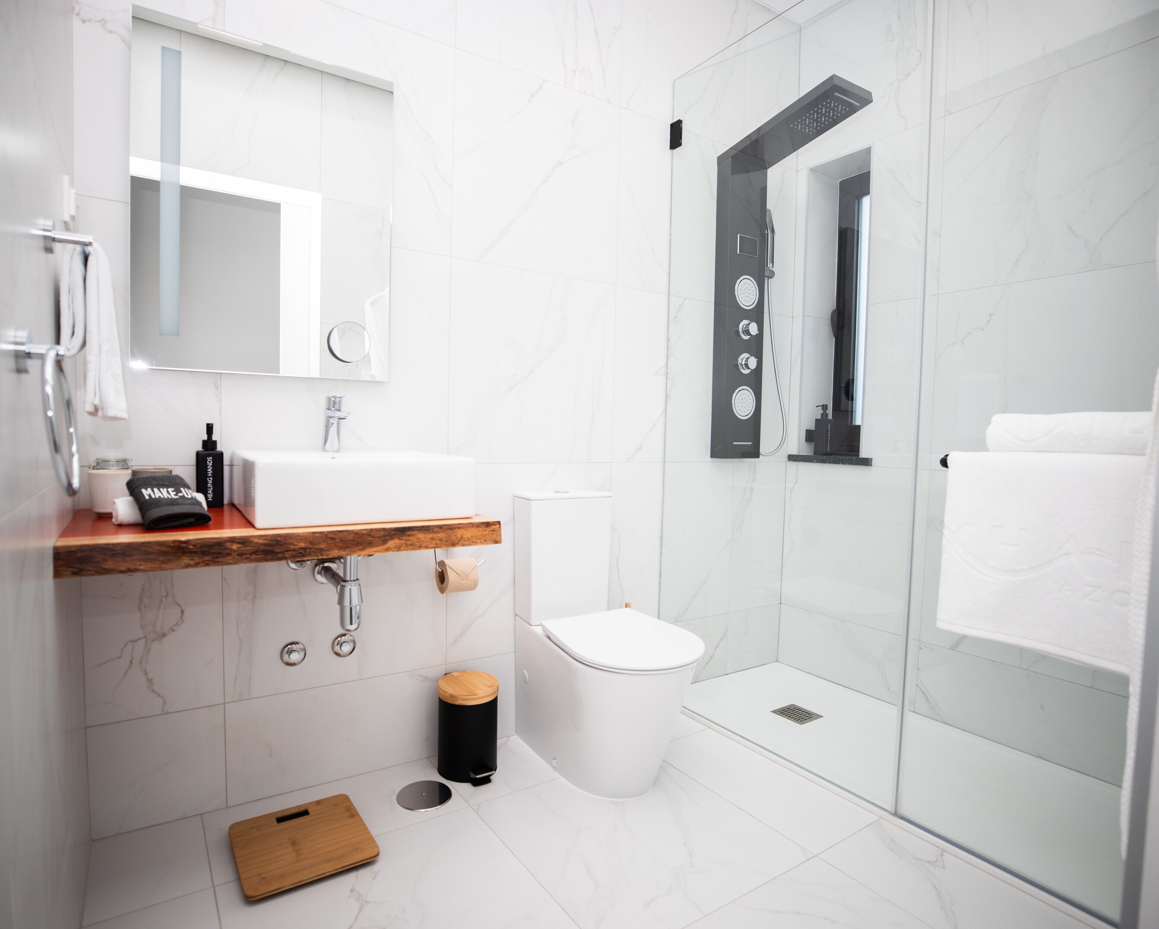 Une salle de bain moderne avec un meuble-lavabo en bois, un lavabo blanc et une cabine de douche en verre.