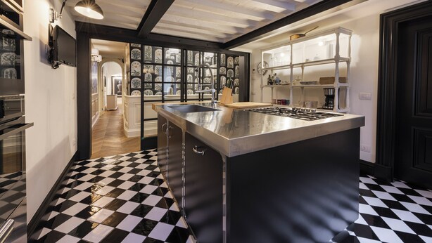 Une cuisine moderne dotée d’un îlot central, d’un sol à carreaux noirs et blancs et donnant sur la salle à manger.