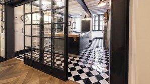 Une cuisine avec un sol à carreaux noirs et blancs, un plan de travail en bois et un meuble avec une porte en verre.
