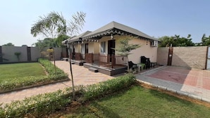 Een gelijkvloers huis met een veranda, een kleine tuin en een geplaveid oprit.