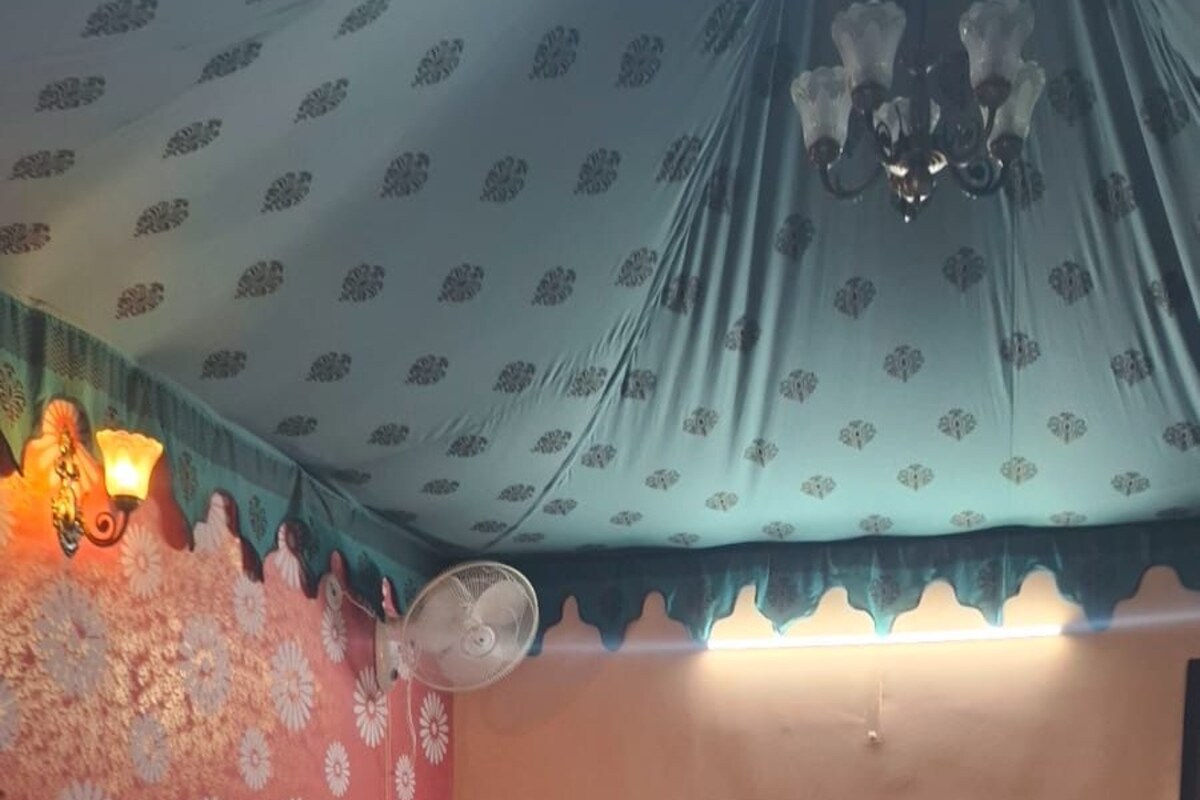 A bedroom with a bed, a fan, and a decorative wall.