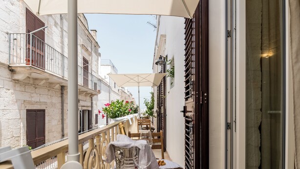 A balcony with a table set for dining, a chair, and a potted plant.