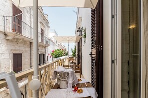 Un balcon avec une table dressée pour le repas, une chaise et un pot de fleurs.