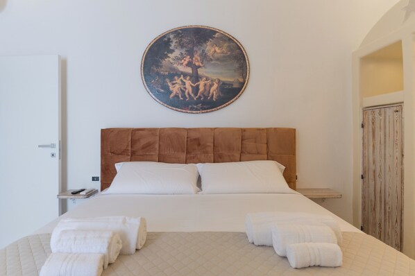 Une chambre d’hôtel avec un grand lit, un tableau rond accroché au-dessus du lit et une armoire en bois.